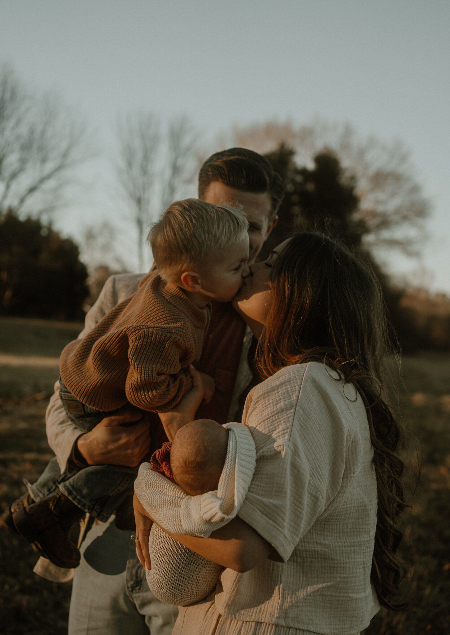 A Tennessee family snuggled together during golden hour for photos in a field.