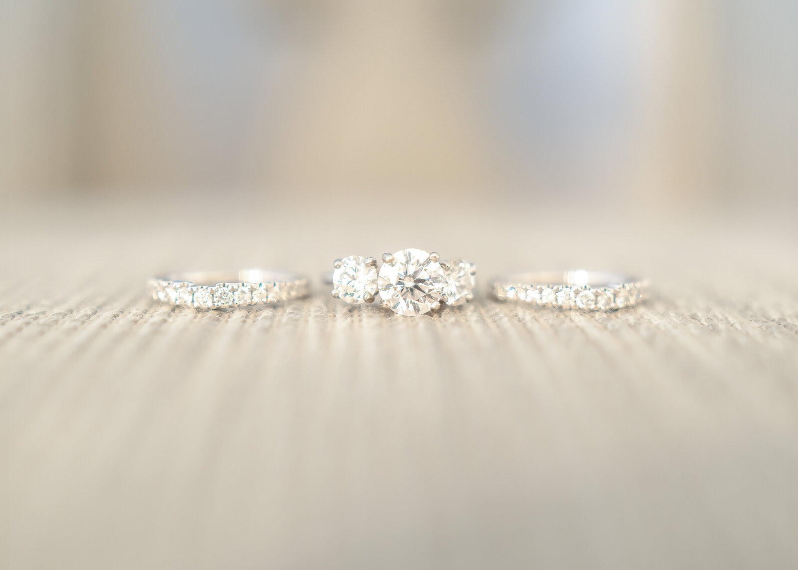 Close-up of an elegant wedding ring set featuring a stunning center stone and two matching bands, beautifully displayed on a rustic wooden surface, perfect for a high-end wedding in Wimlington, NC.