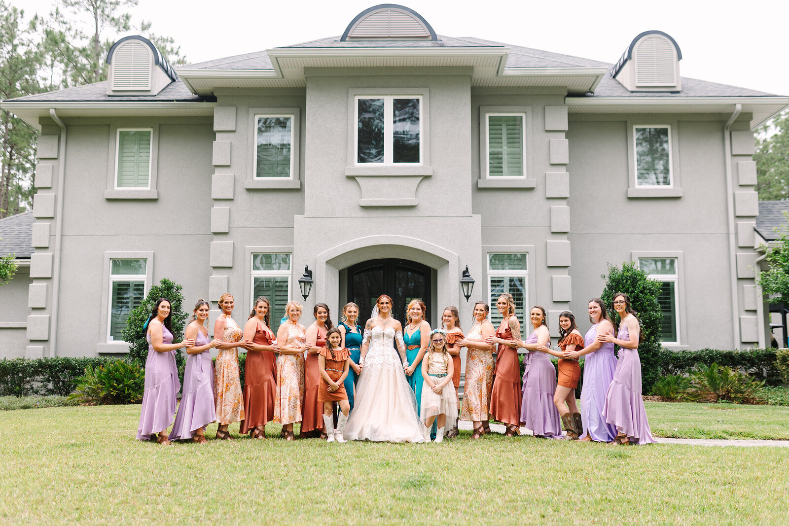 A 17 person bridal party just the brides side all wearing different colors some with beautiful floral patterns