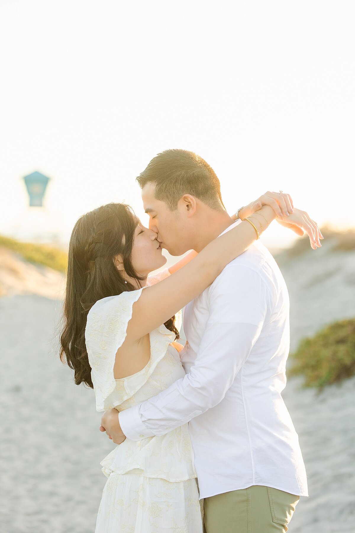 Engaged couple kissing at their engagement photography session on the sand dunes in Coronado.