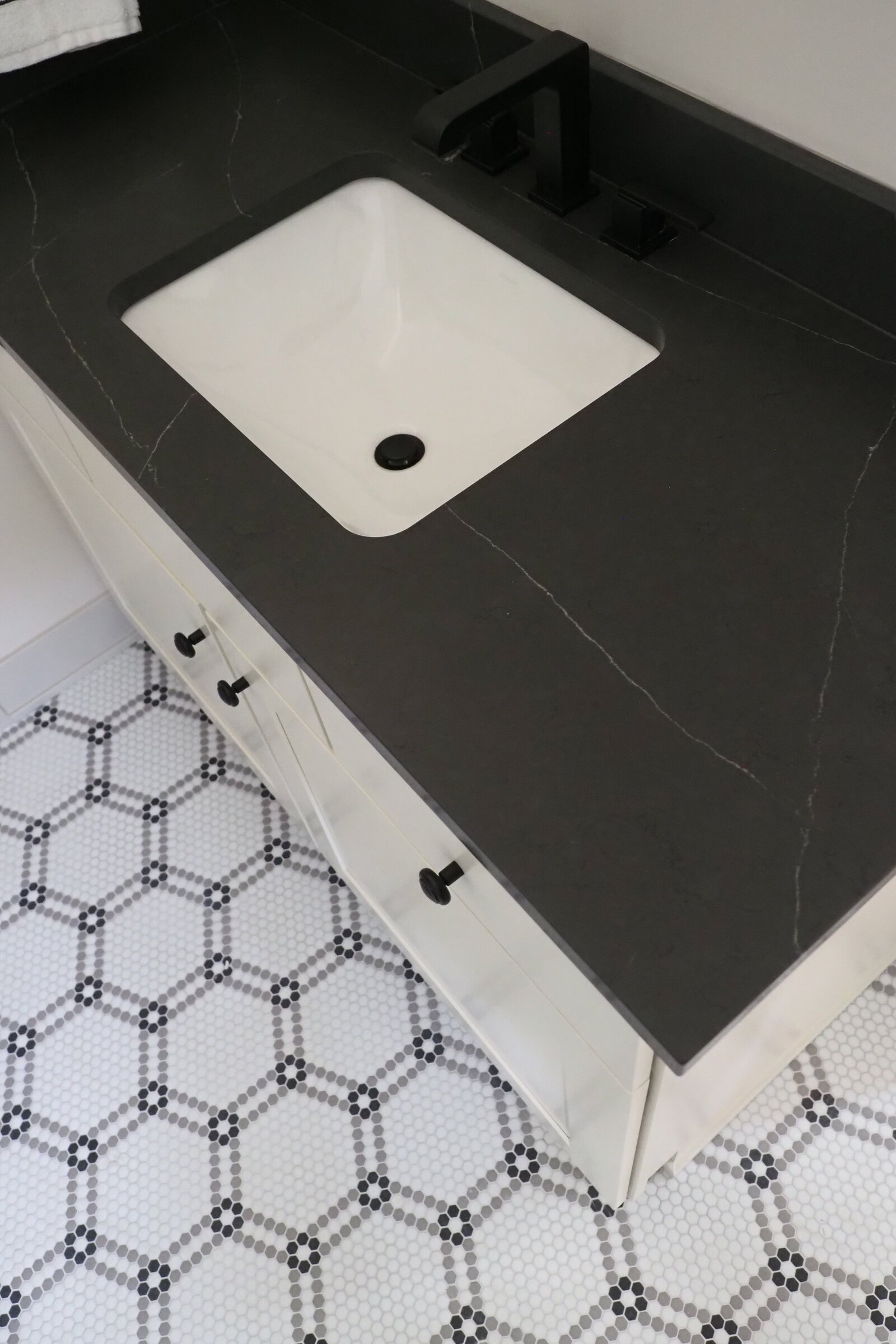 Black countertops with mosaic tile floor in black and white.