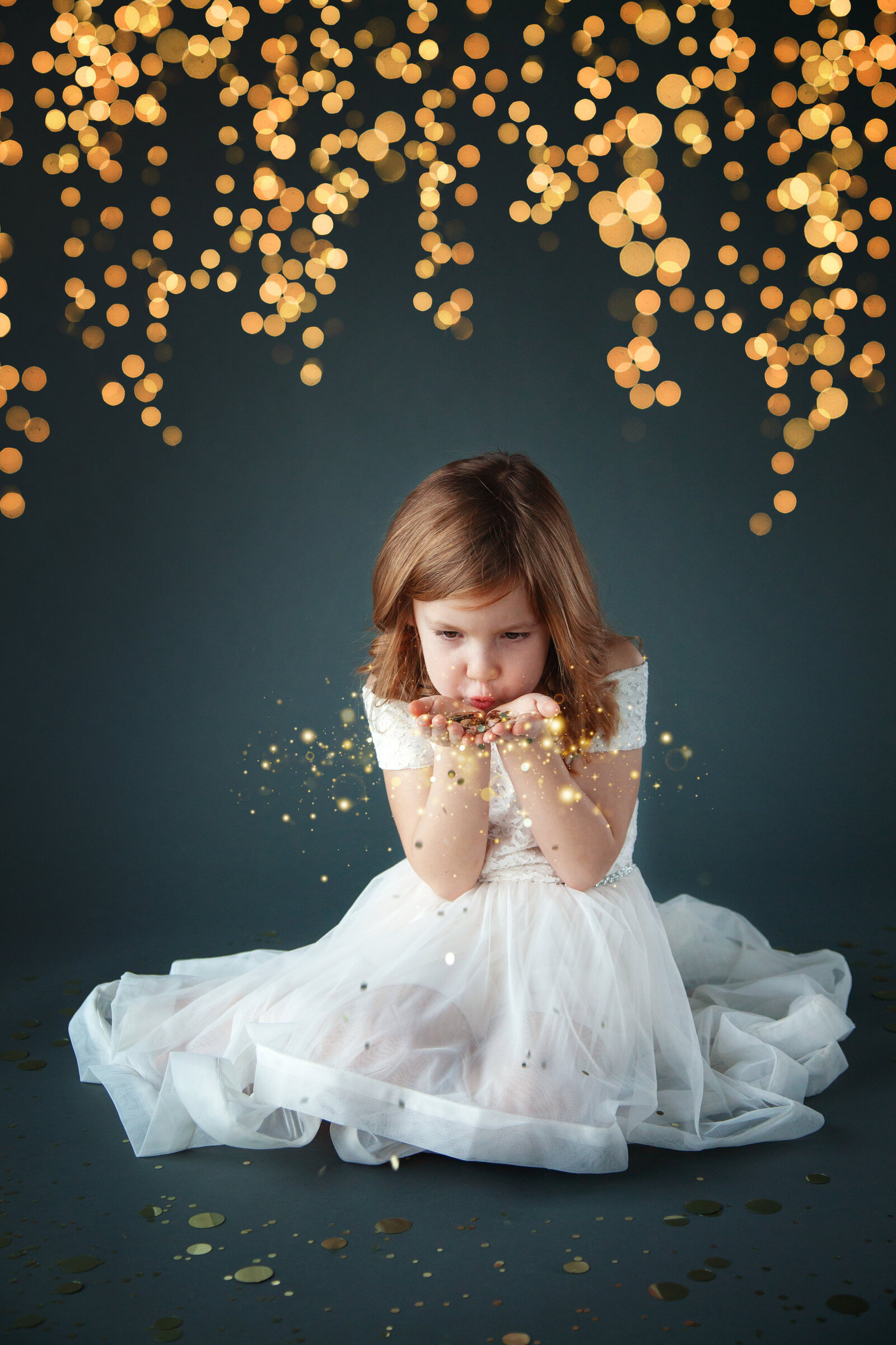 Girl in dress blowing glitter with gray background.