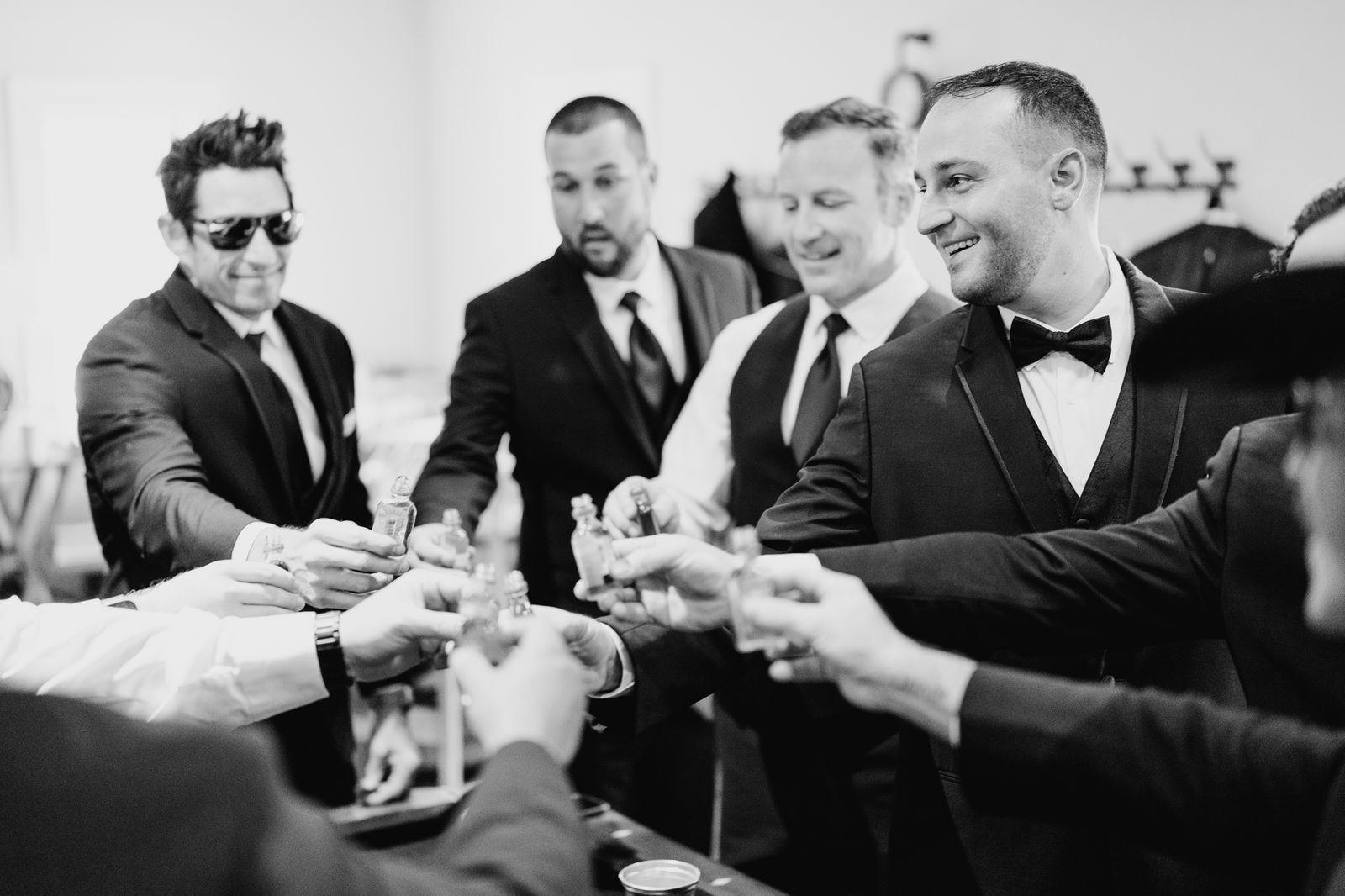 Groom and groomsman cheersing shots in black and white