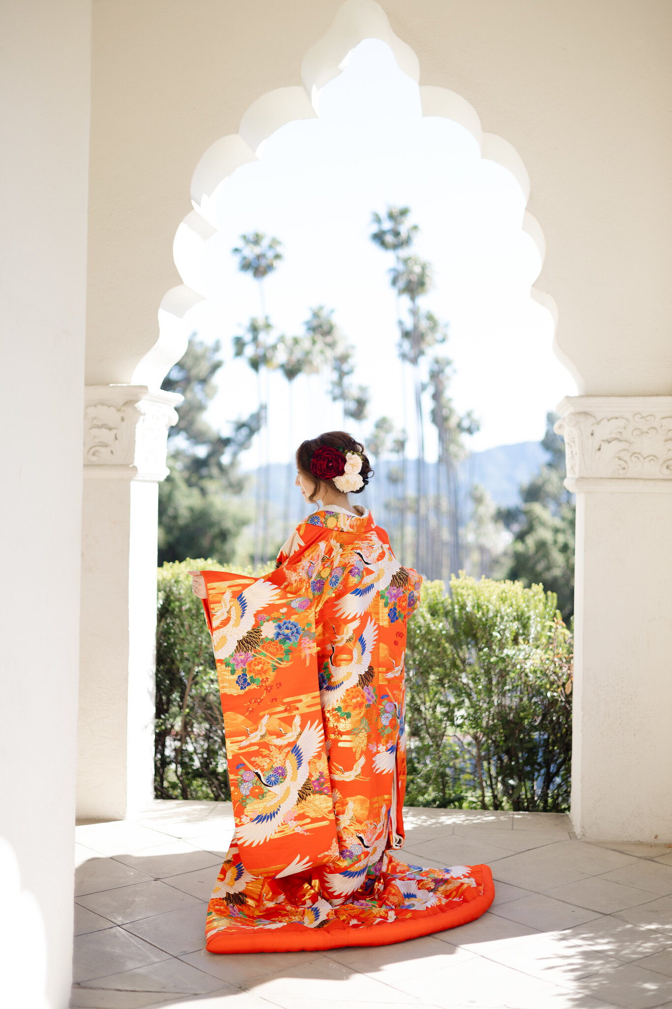 Back view of bride in crane patterned iro uchikake framed by arch at Brand Park Glendale, Los Angeles California. Available for wedding kimono rental | 鶴柄の色打掛をまといアーチに映える後ろ姿の花嫁、ブランドパーク・グレンデール。ロサンゼルス カリフォルニアの和装着物レンタル