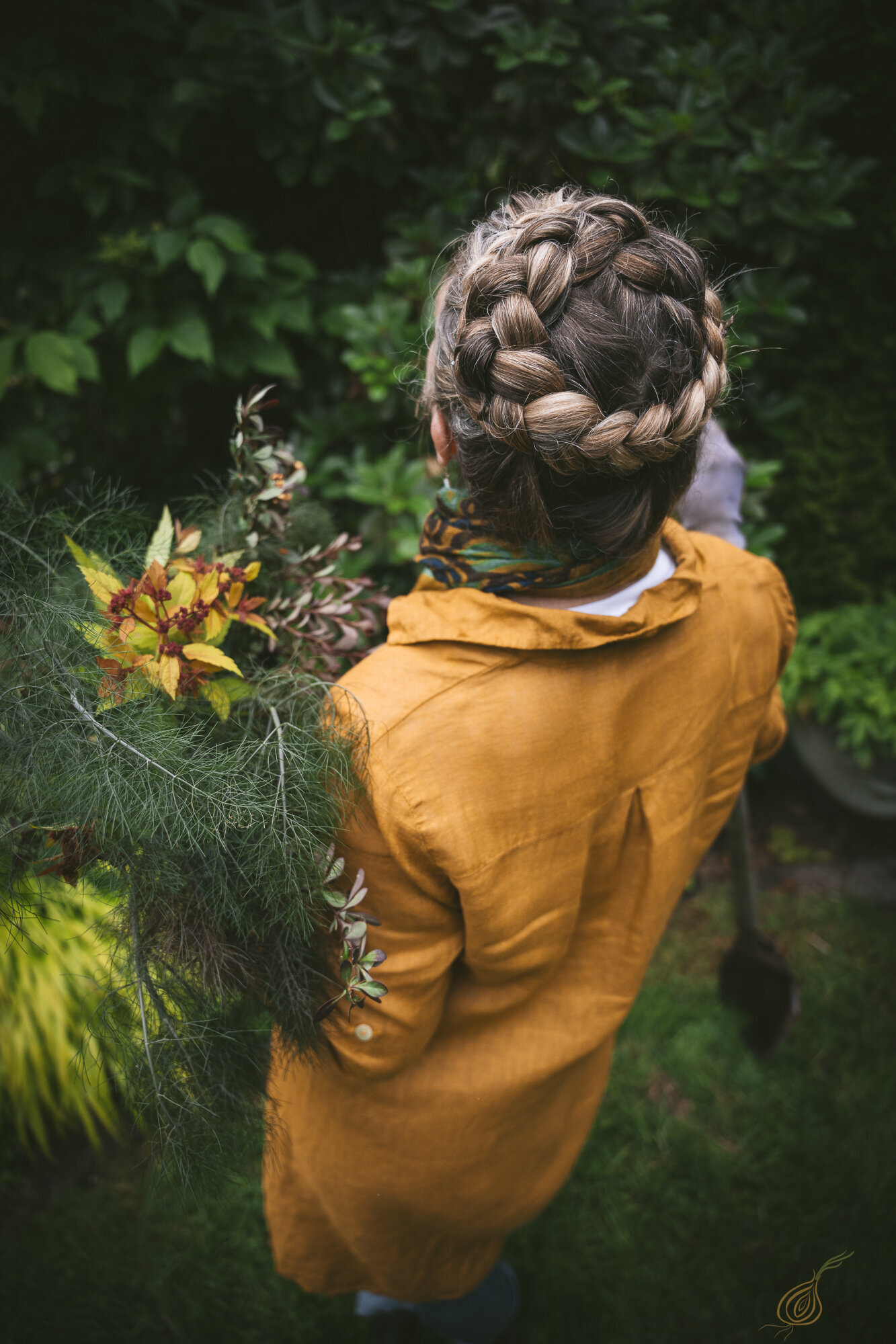 A woman with a braid in her hair gracefully holds a vibrant bouquet of flowers, showcasing her natural beauty and elegance.