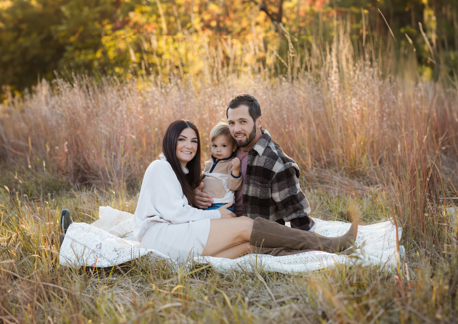 mom and dad sitting on lace blanket with son for family photos cleveland family photography