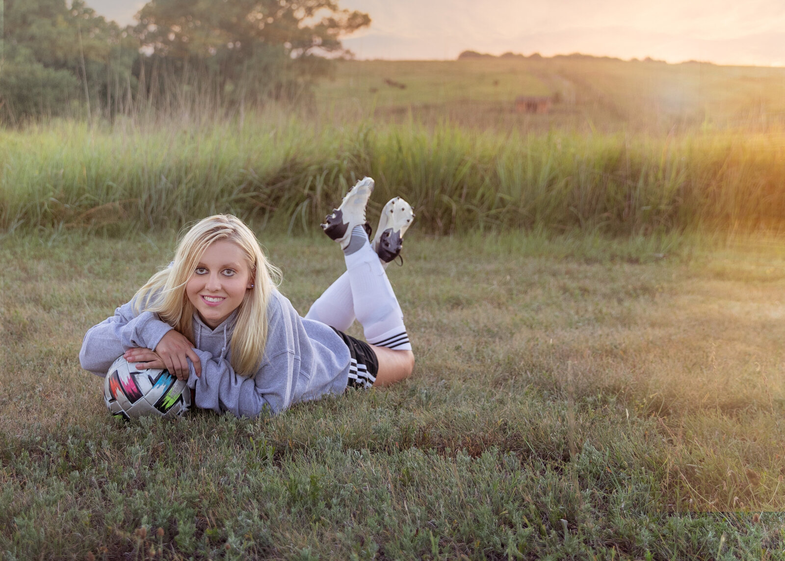 Jorrian lays on the ground holding her soccer ball