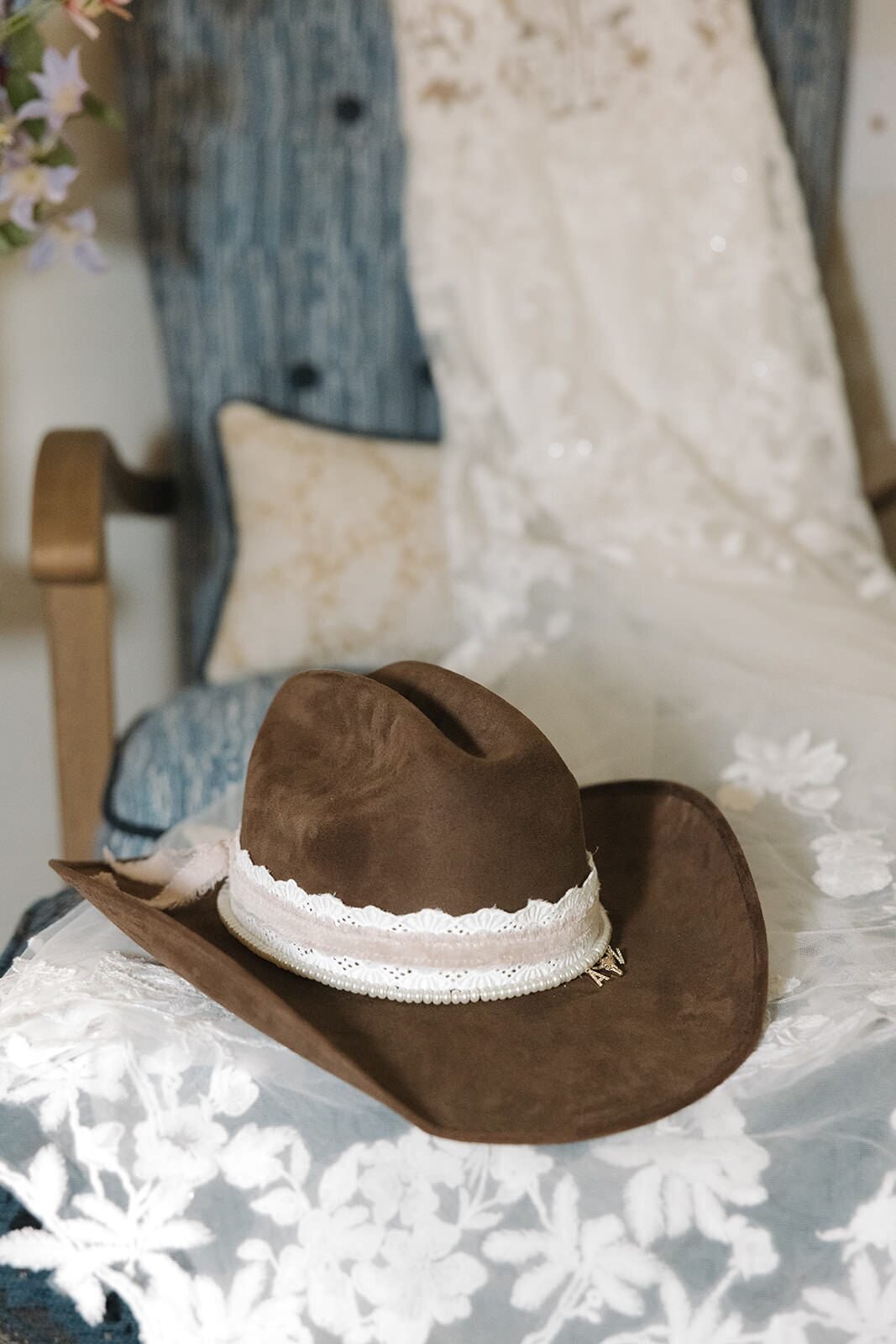 Brown cowboy hat with lace and pearl trim on the wedding dress