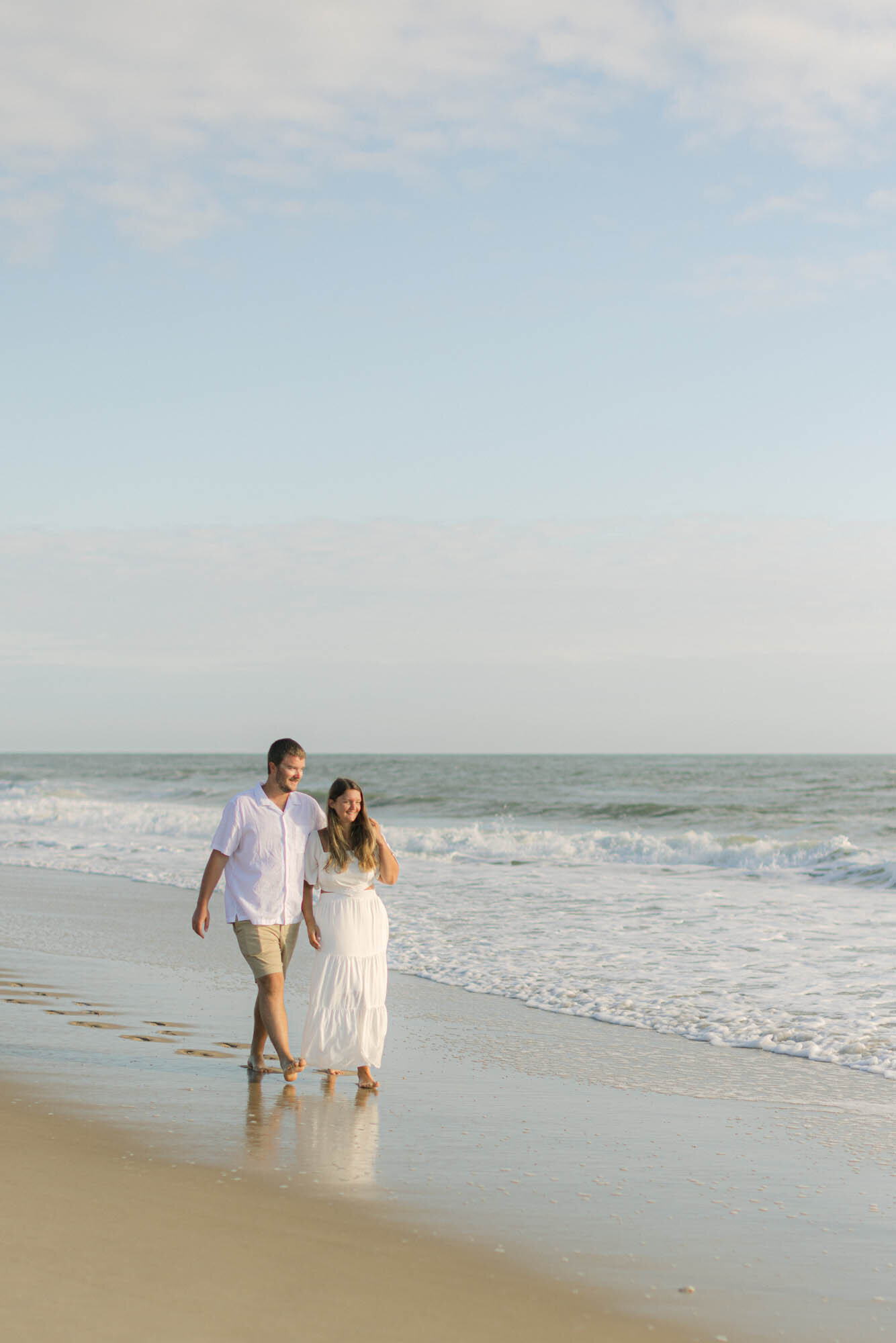 Couple walking on the Outer Banks beach during their engagement photo session