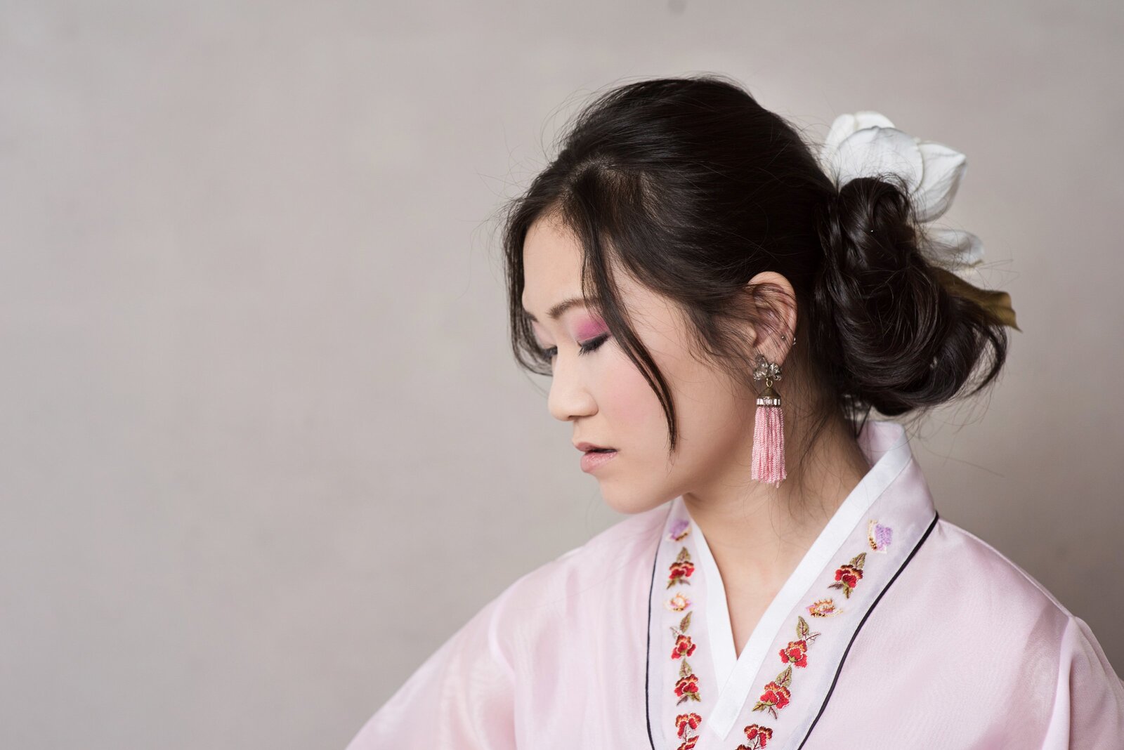 high school senior photo of girl in traditional korean clothing in front of backdrop in studio