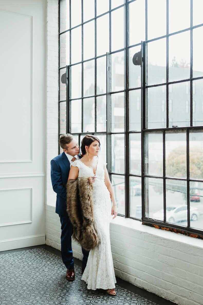 Newlyweds share and intimate moment while standing in a large industrial window