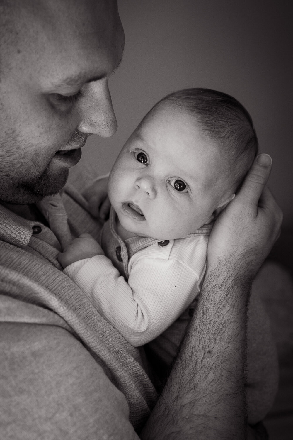 Zwart wit close up van vader en baby - knuffelmomentje newbornshoot.