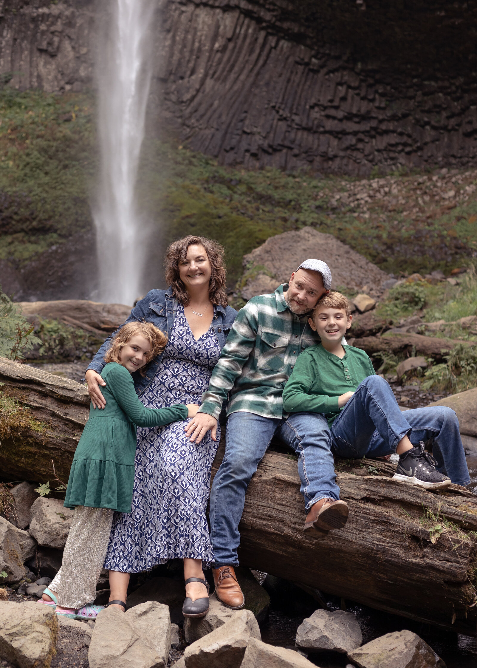 Family of four sitting on log in front of Latourell Falls in the Columbia River Gorge Oregon