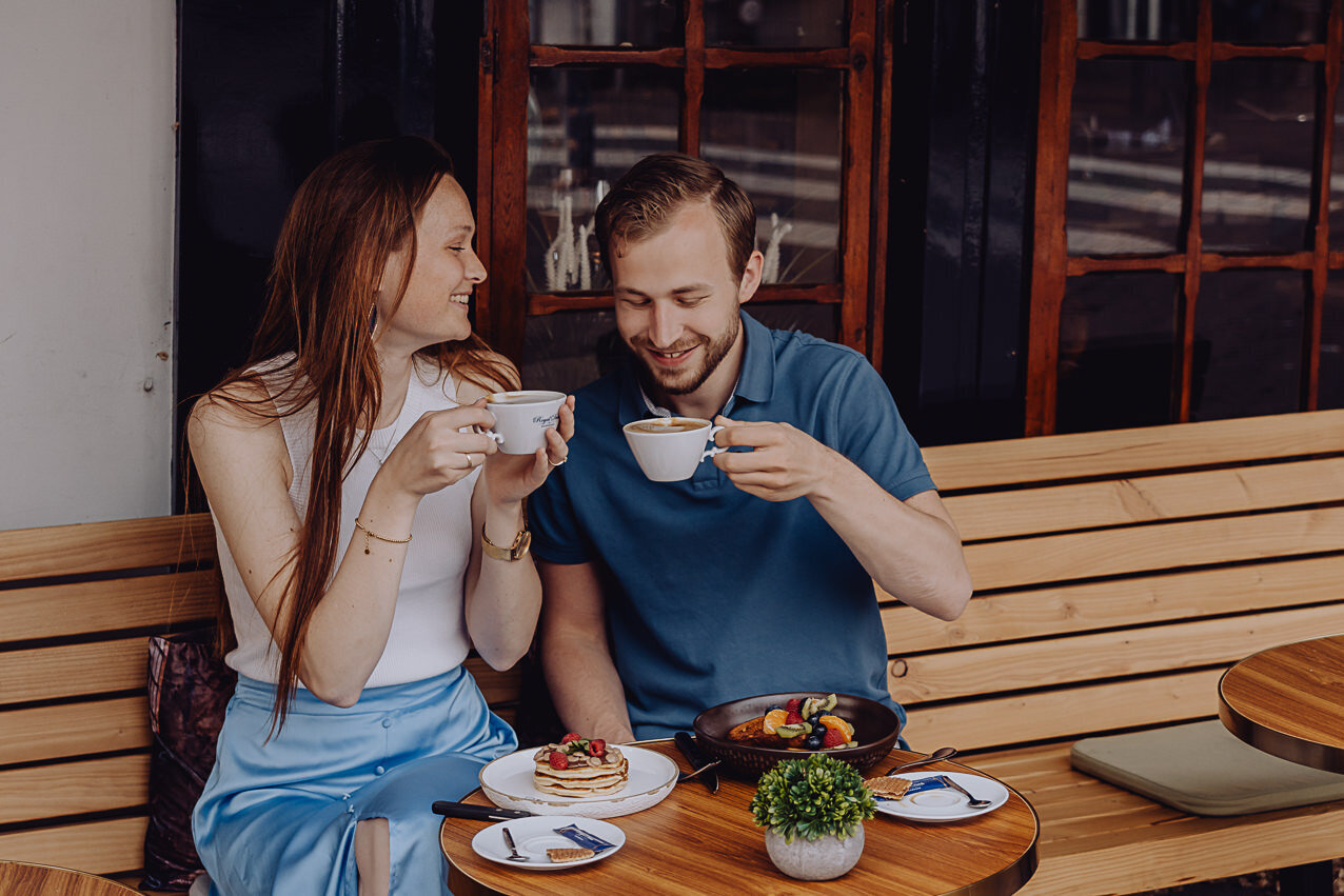 Stel zit op het terras voor de winkel koffie te drinken