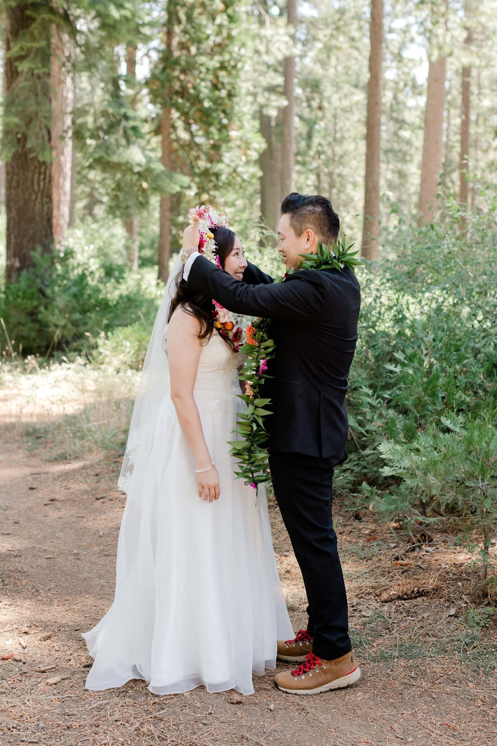 A groom places a traditional hawwaiin lei on his bride during their mountain wedding. 