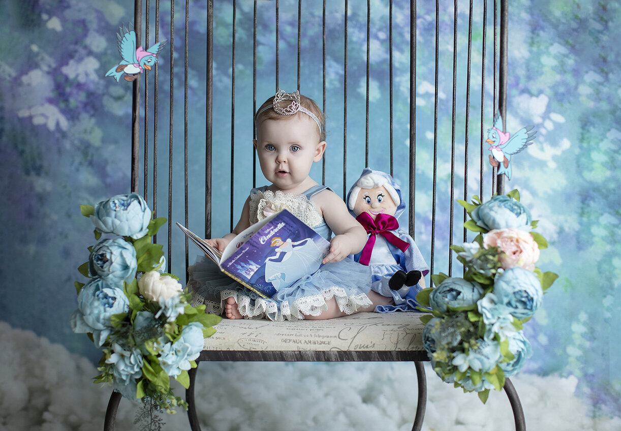 Baby girl holding Cinderella book at her 1st birthday photoshoot.