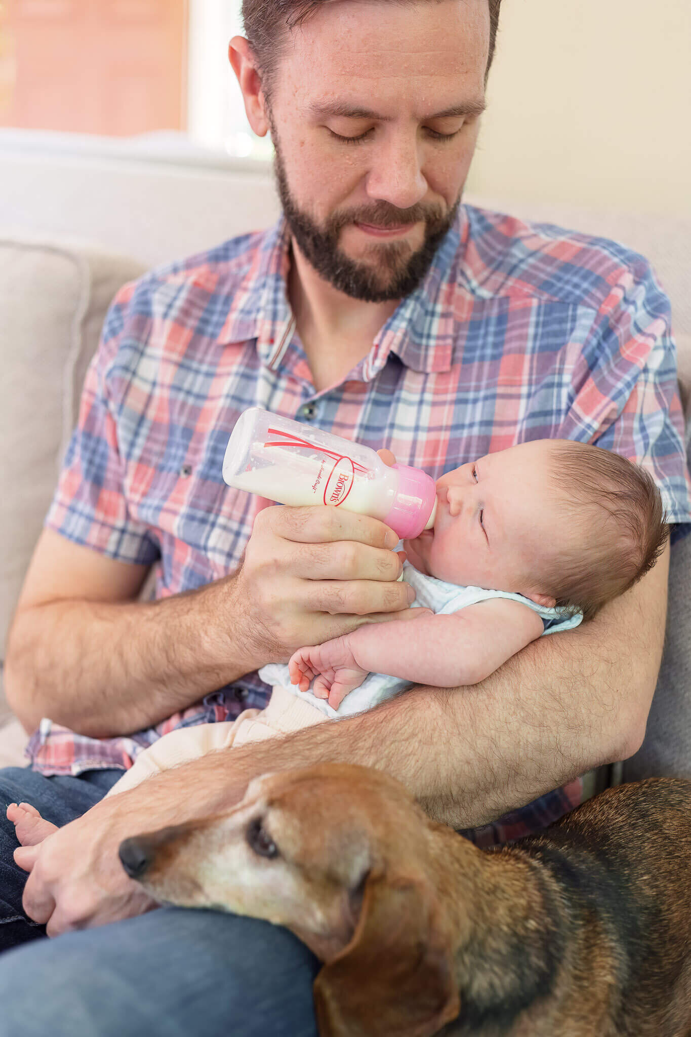 A dad feeding his newborn daughter a bottle.