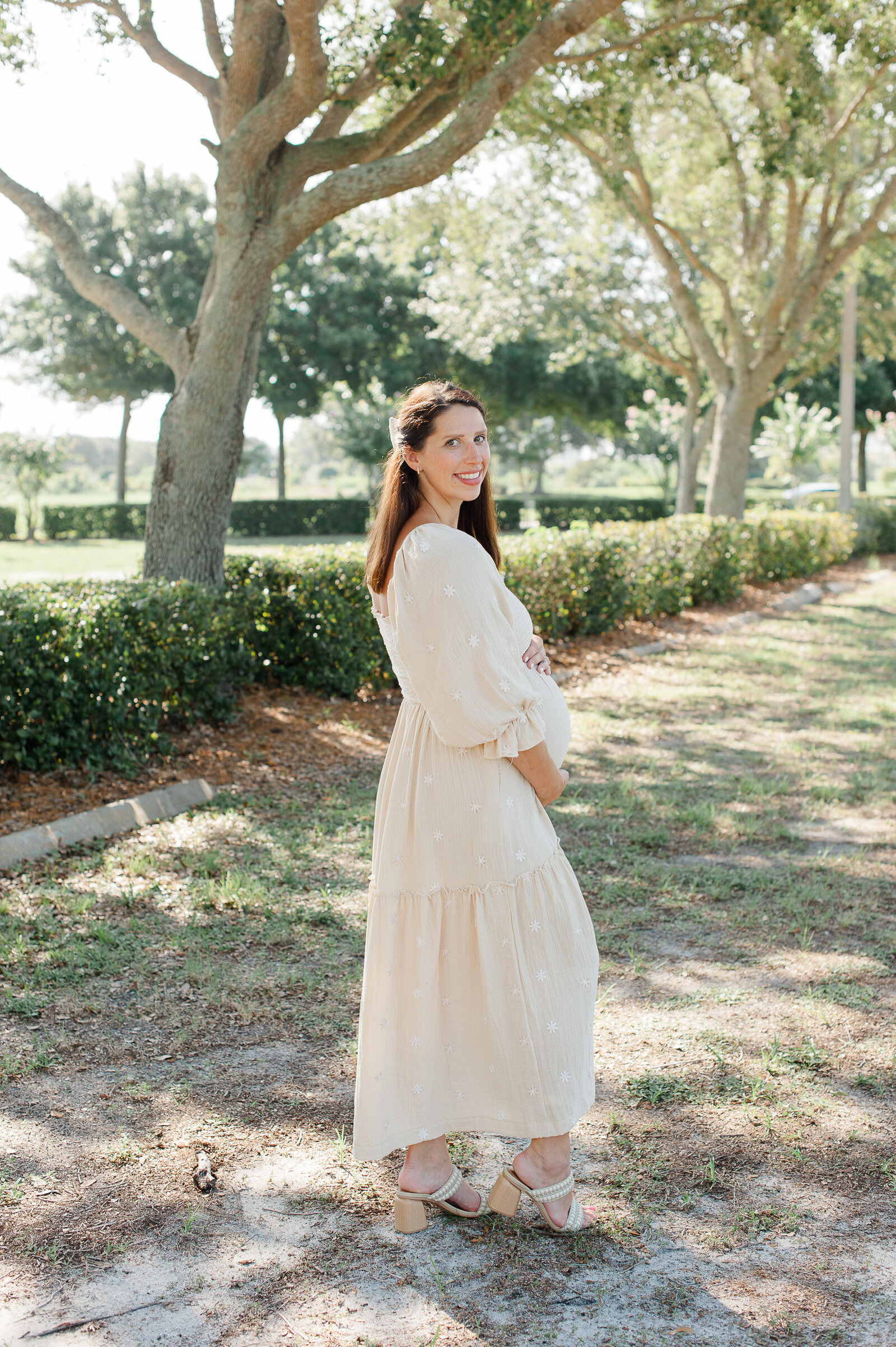 Pregnant mother smiles at the camera looking over her shoulder during maternity photos