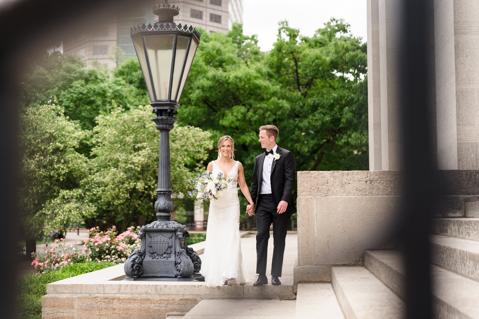 Bride and groom walk along the steps of the Ohio Statehouse framed by the iron railing