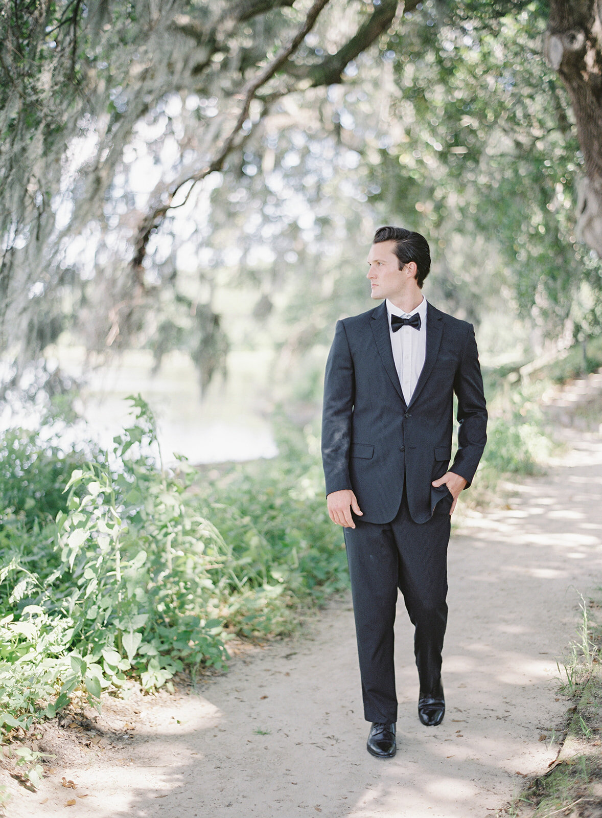 Groom walking down a path under oak trees. Photographed by wedding photographers in Charleston Amy Mulder Photography