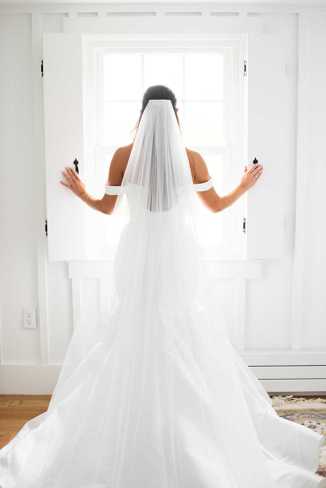 bride in white dress looking out of light filled windows in newlywed suite at Windridge