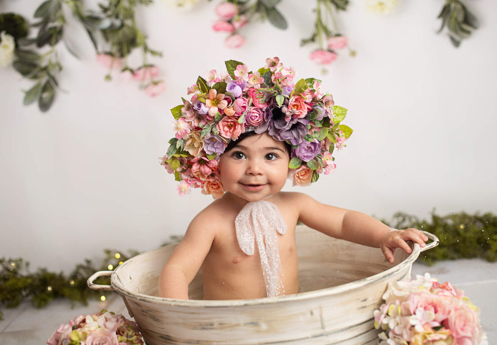 Baby girl with floral bonnet in tub