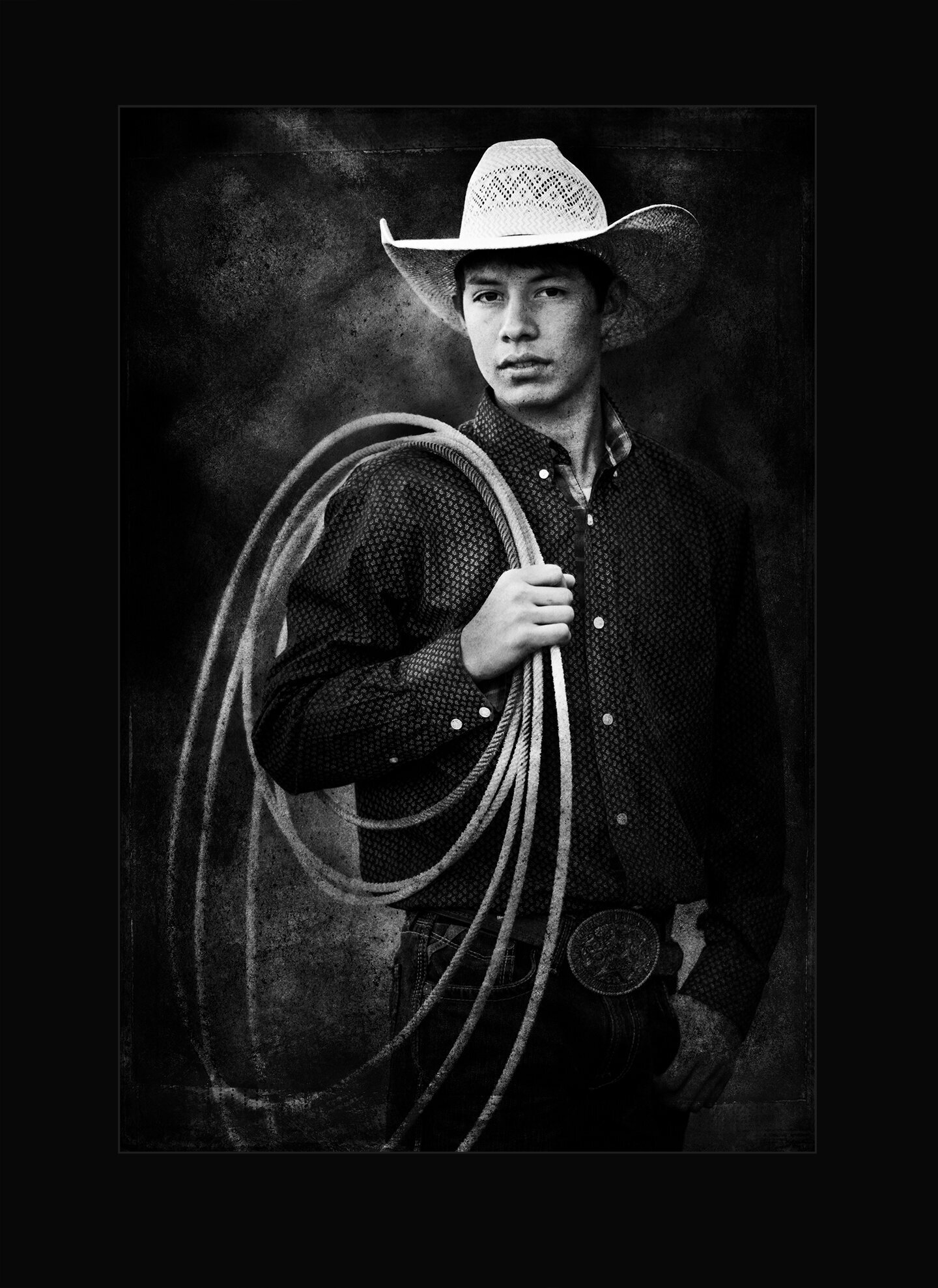 black and white picture of cowboy holding a rope in billings montana getting his graduation pictures taken.