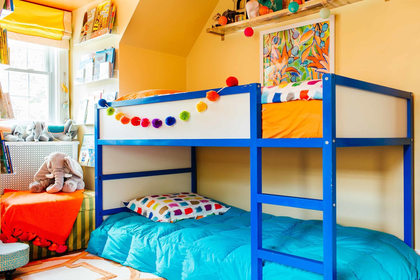 A boys bedroom with blue bunk beds and pom pom garland.