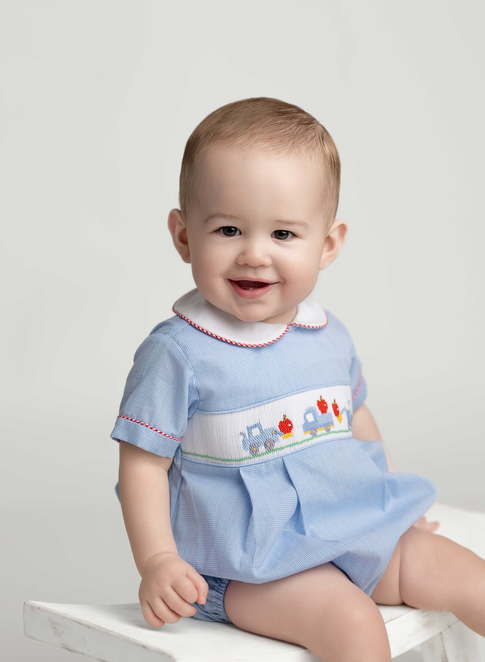 Baby boy in smocked blue outfit smiling for an heirloom portrait. Heirloom photo taken by Jenni Nikki Photography in Atlanta, GA.