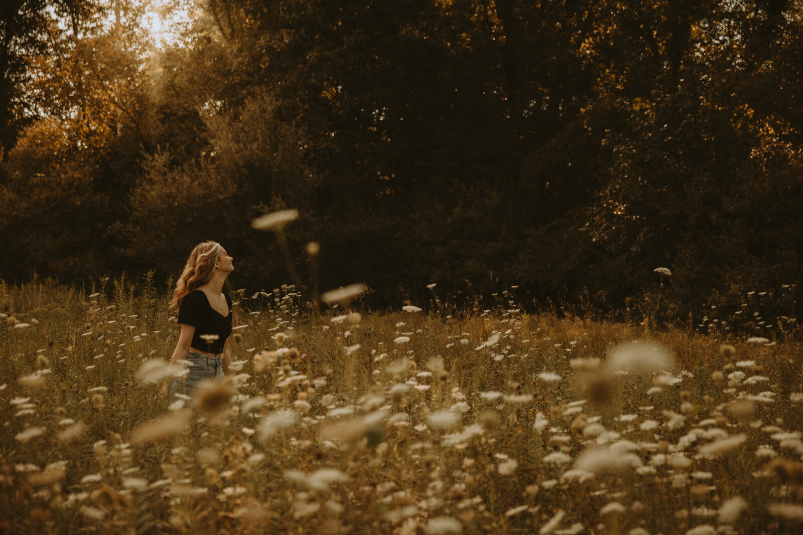 A groom carries his bride across the dancefloor under a twinkle-light lit tent while her veil flows and they smile