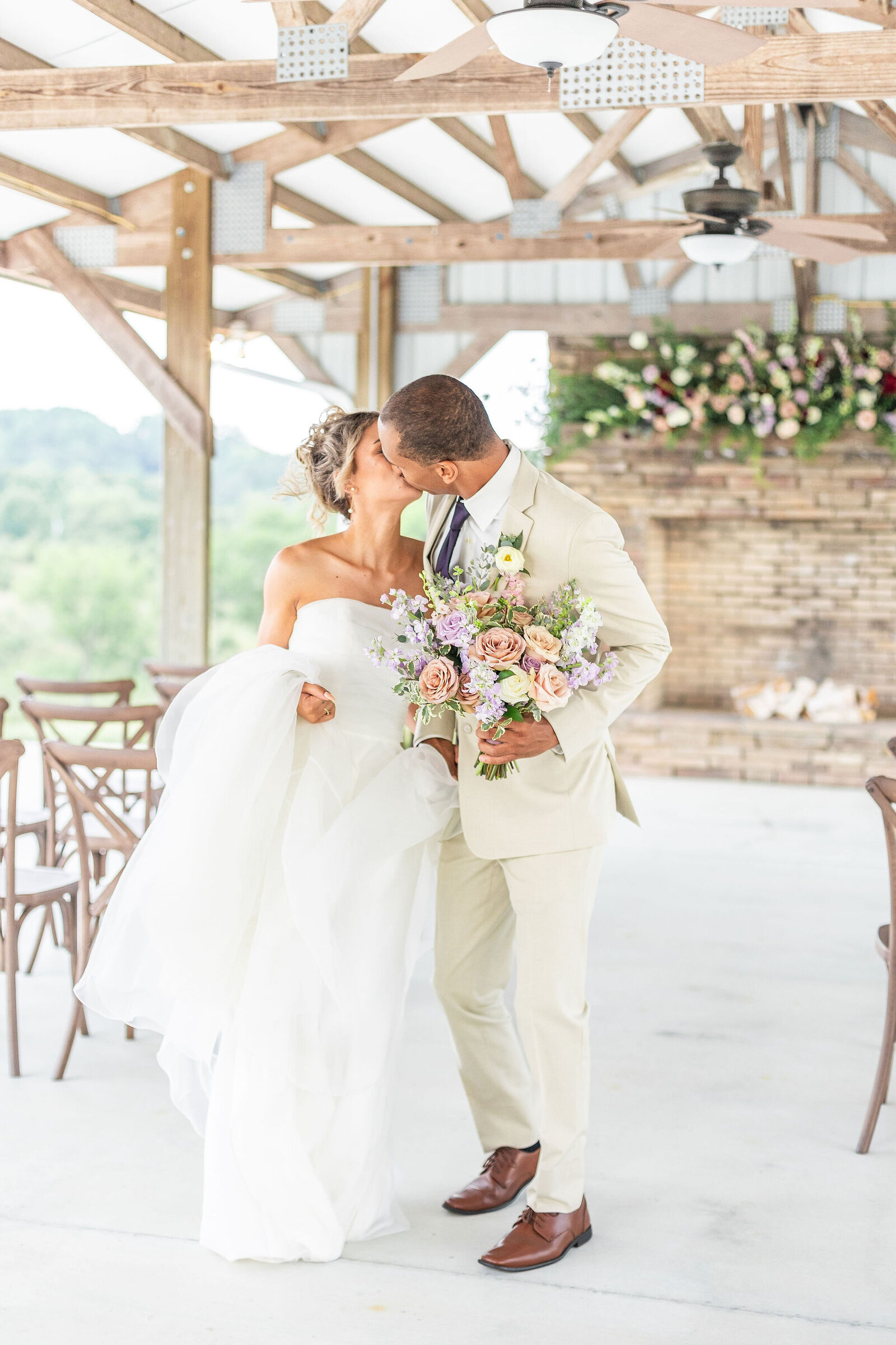 Bride and groom sharing a romantic moment in the rustic pavilion at Willow and Stone Events, surrounded by floral arrangements and countryside views.