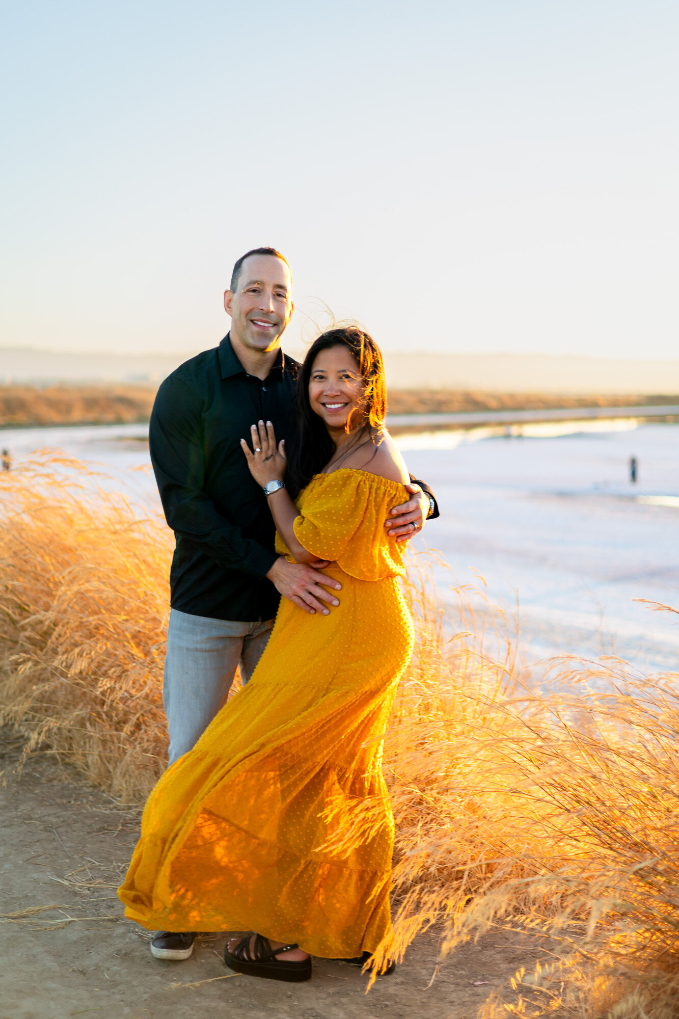 Couple standing in tall grass, glowing in golden light, with the woman’s dress flowing – Bay Area Couples Photography Portfolio - Ellobelle Photography