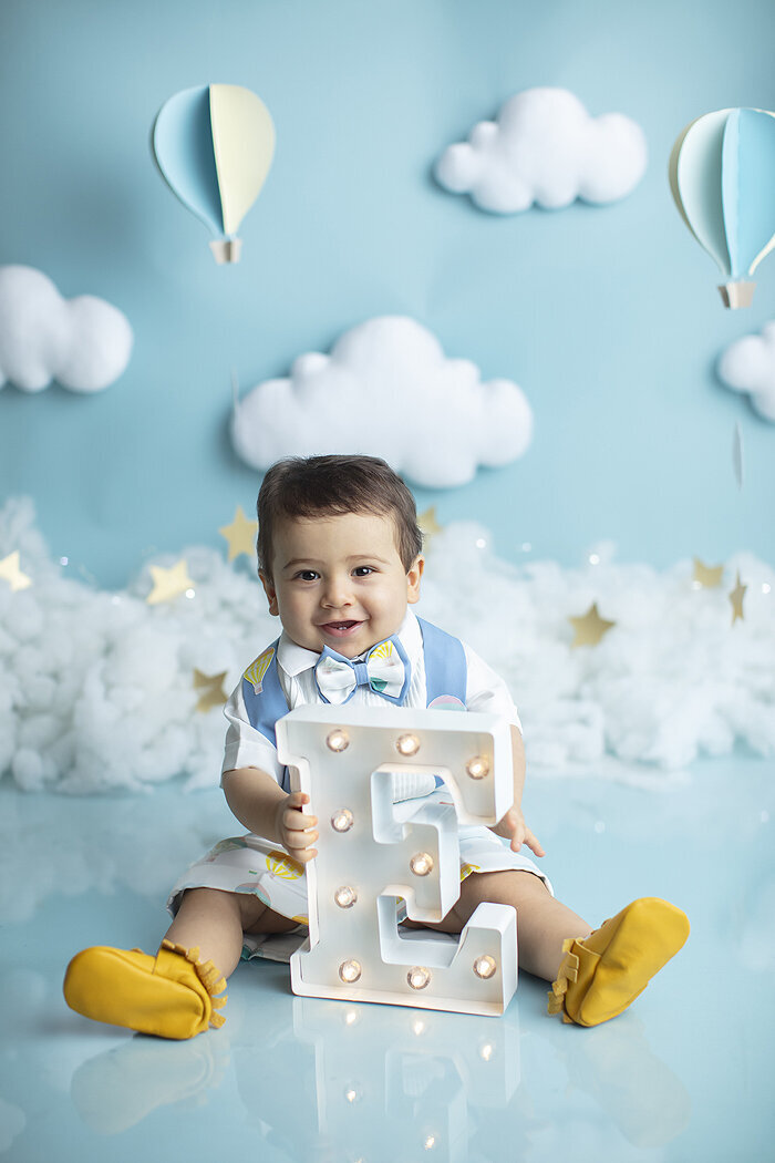 Baby boy holding letter E at his first birthday photoshoot.