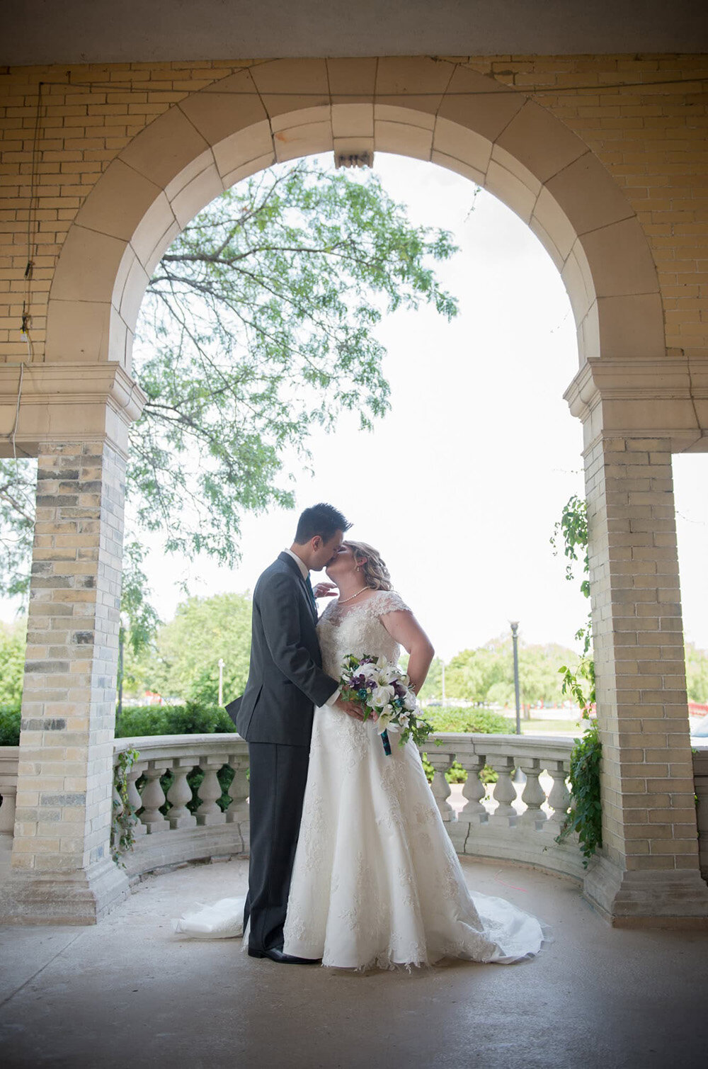 wedding couple kiss under brick archway