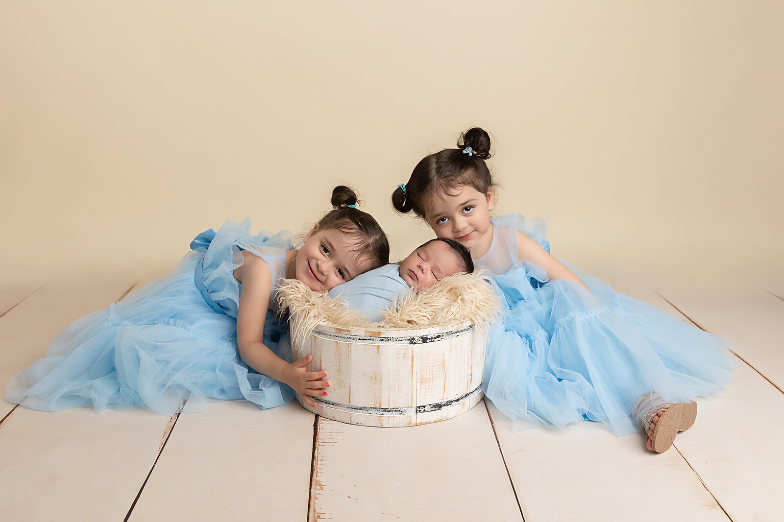 little girls in blue with new baby brother by Newborn Photography Bucks County PA