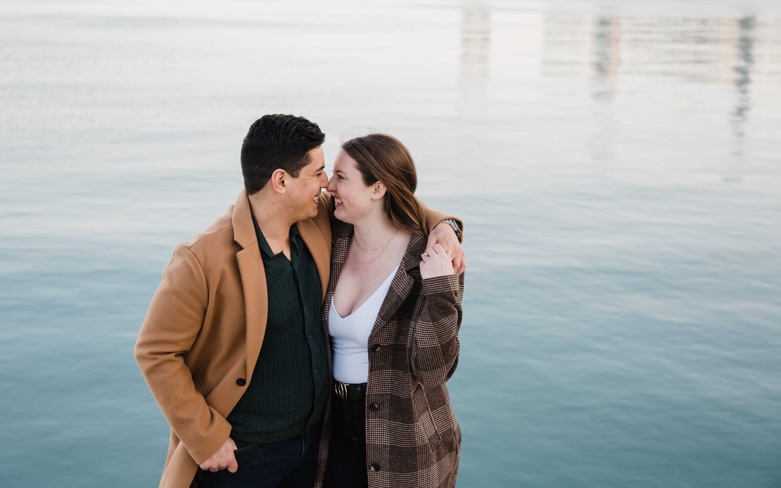 Engagement session couple smiling at each other in front of lake Michigan