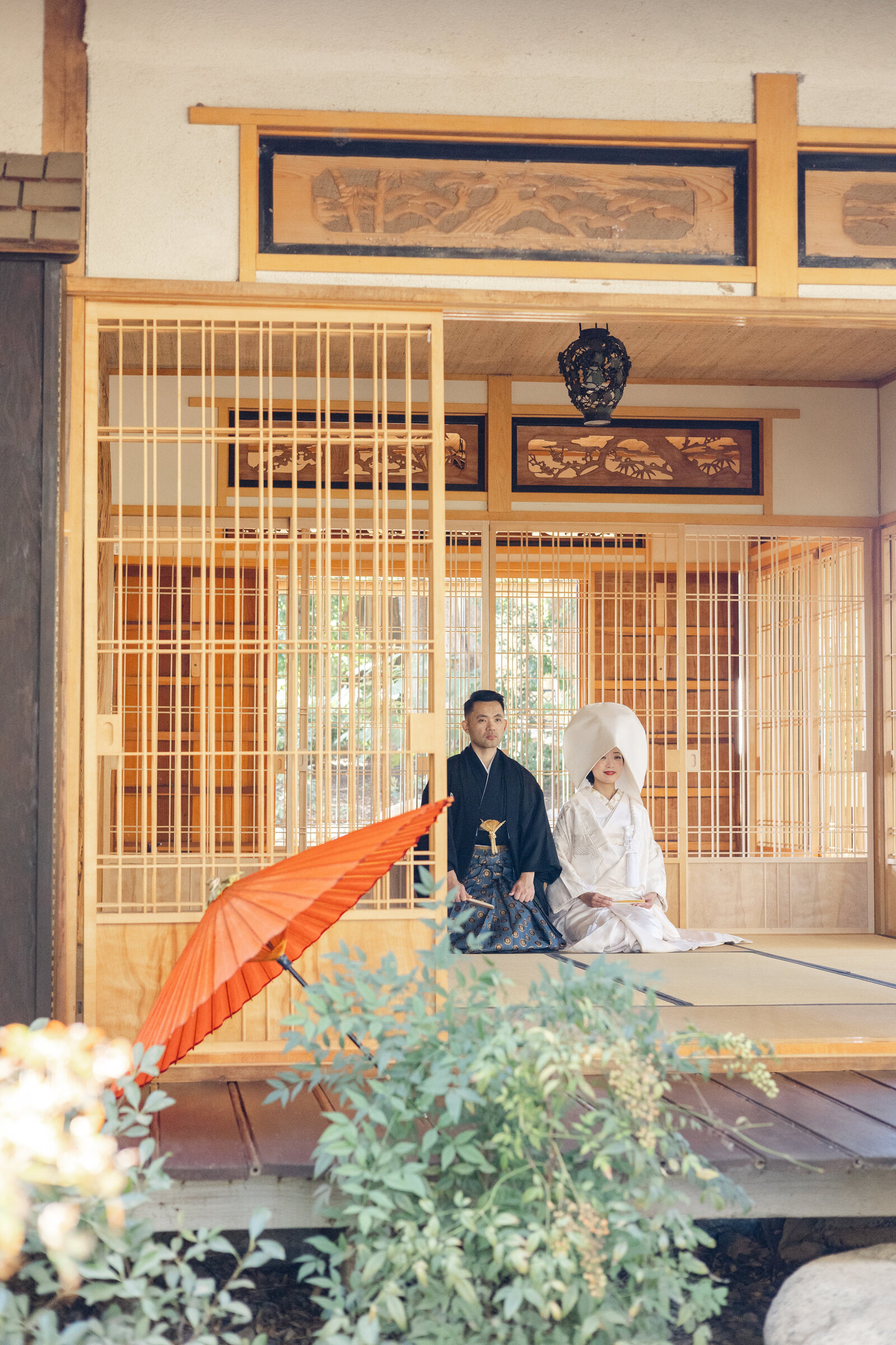Bride in shiromuku on engawa with red umbrella at Storrier Stearns | 着物レンタル 和婚 白無垢 赤い和傘 ロサンゼルス ストーリア・スターンズ日本庭園