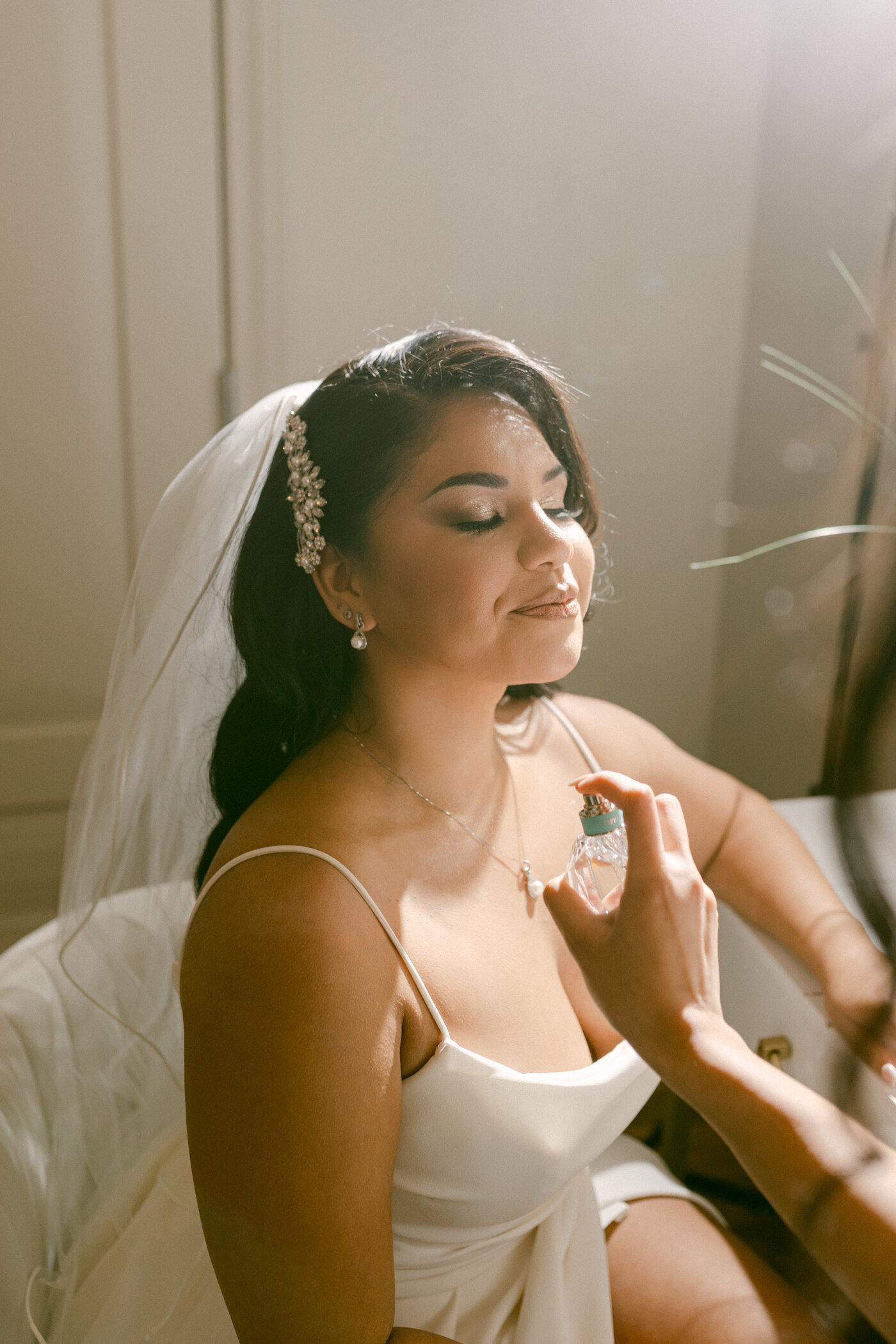Bride is sprayed with perfume while getting ready for her Fort Worth wedding