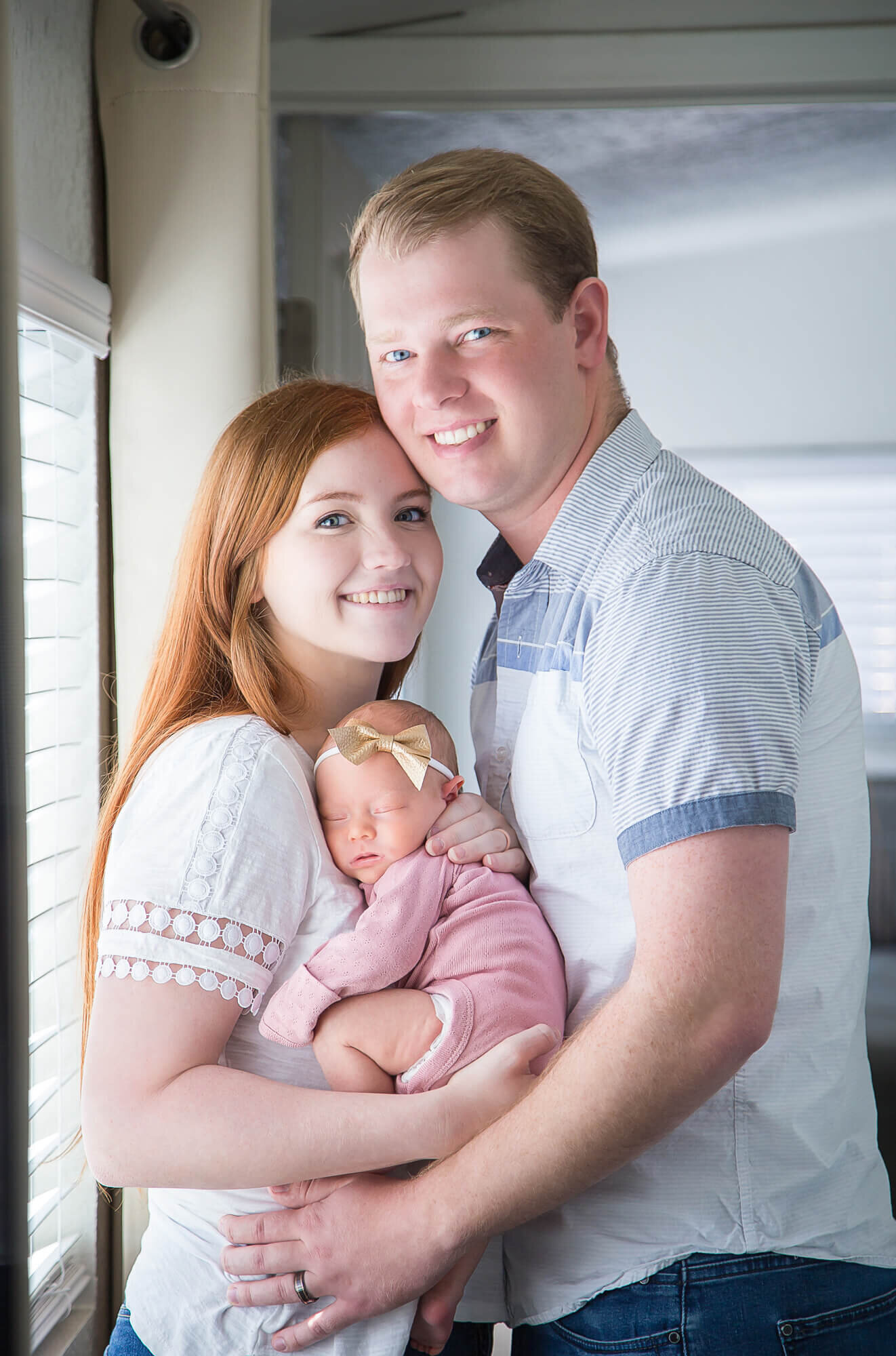 Beautiful couple posing in their home with newborn baby girl in pink