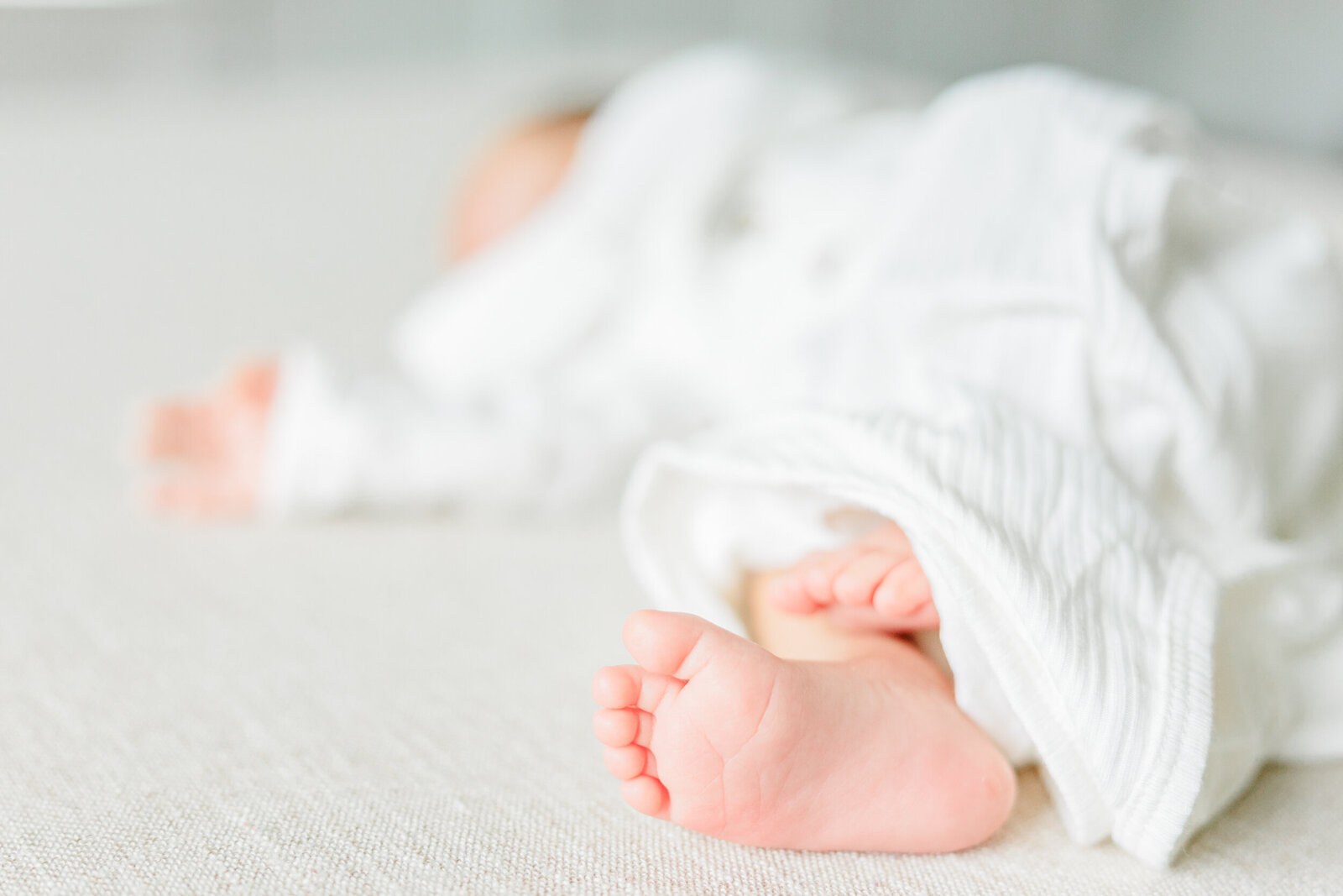 Sleeping newborn baby boy's toes in a white gown