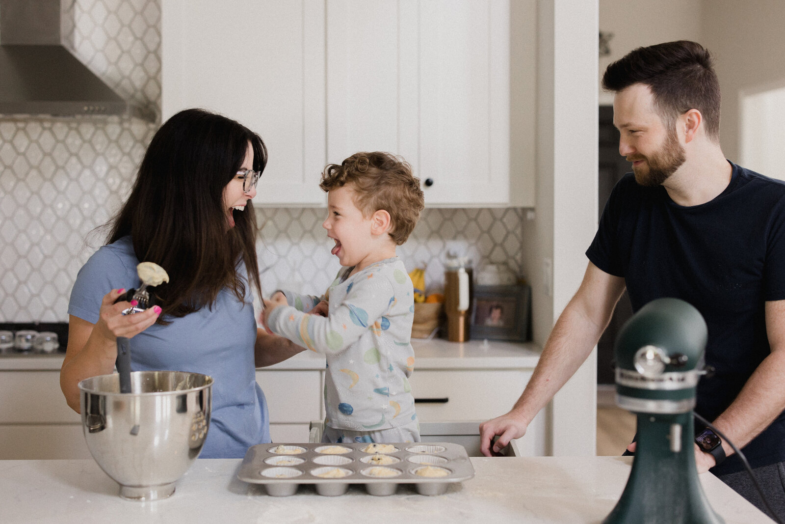 Mom and son make silly faces while baking together with dad