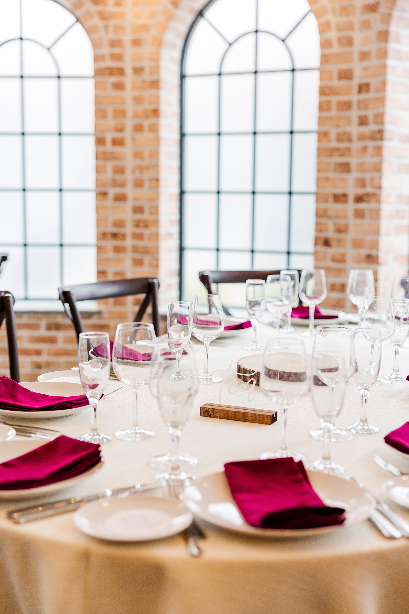 Close-up of Perona Farms reception table decor featuring burgundy napkins, glassware, and candlelight.