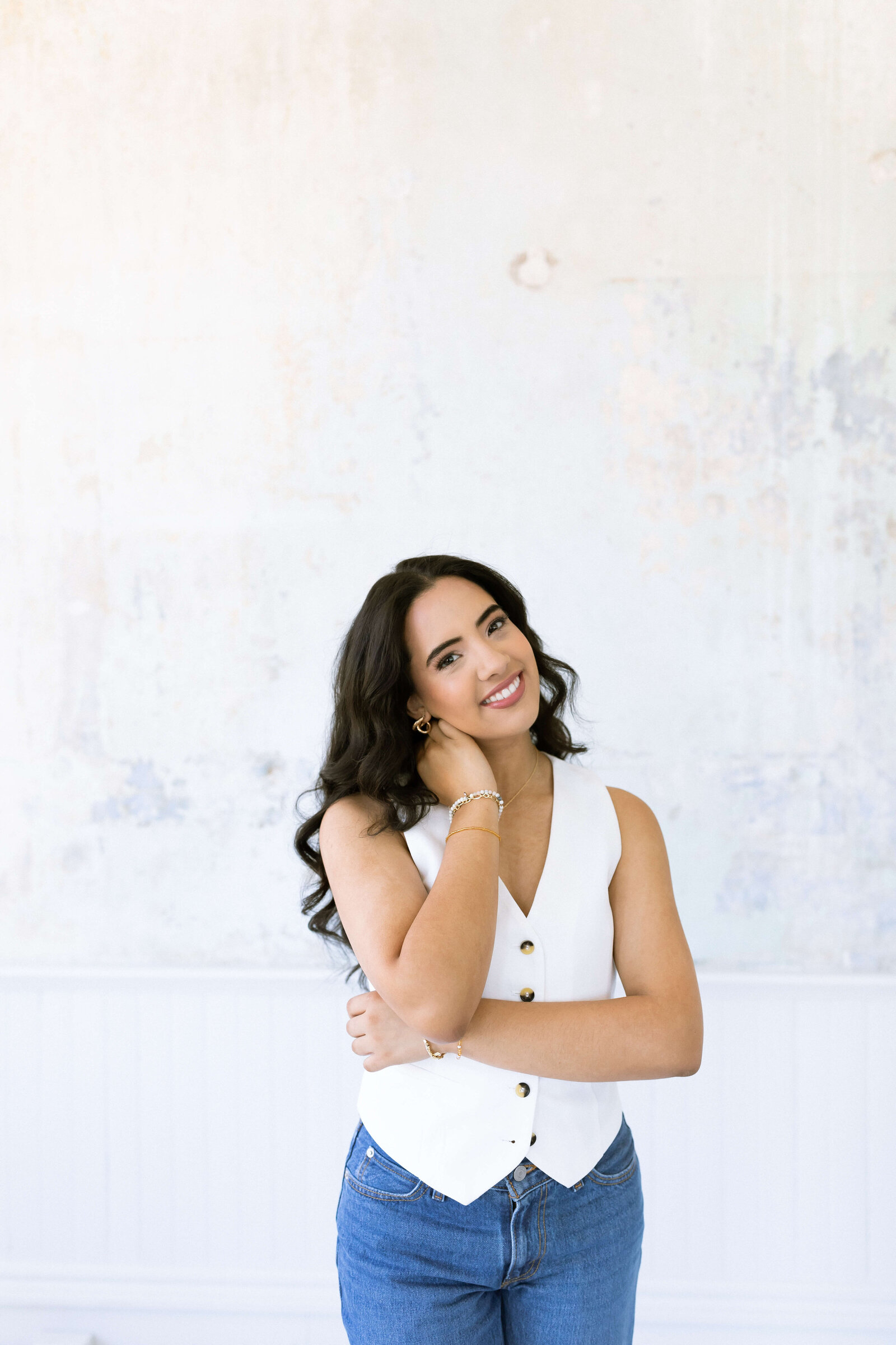 dark haired girl posing for senior pictures and wearing a white shirt and blue jeans