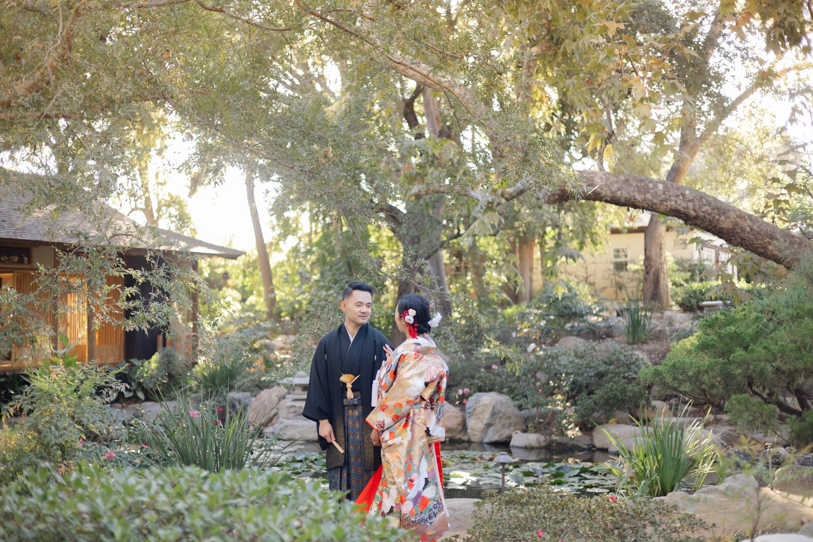Romantic scene of bride and groom gazing at each other beside the koi pond at Storrier Stearns Japanese Garden, kimono rental in Los Angeles | ロサンゼルスStorrier Stearns Japanese Gardenの池のほとりで見つめ合う着物レンタル新郎新婦