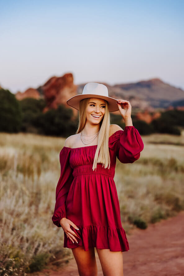 Girl in red dress and a hat poses at Red Rocks Park.