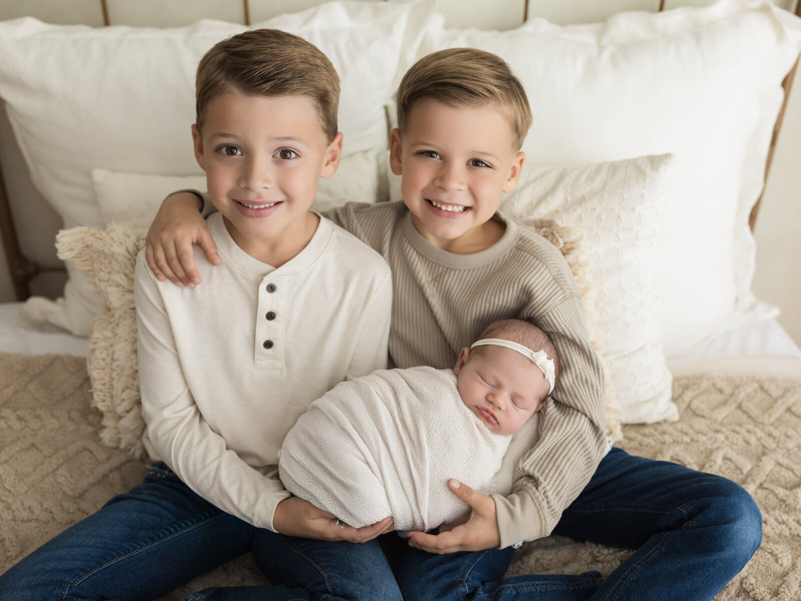 brothers holding newborn baby girl swaddled in white wrap for newborn studio portraits cleveland newborn photographer