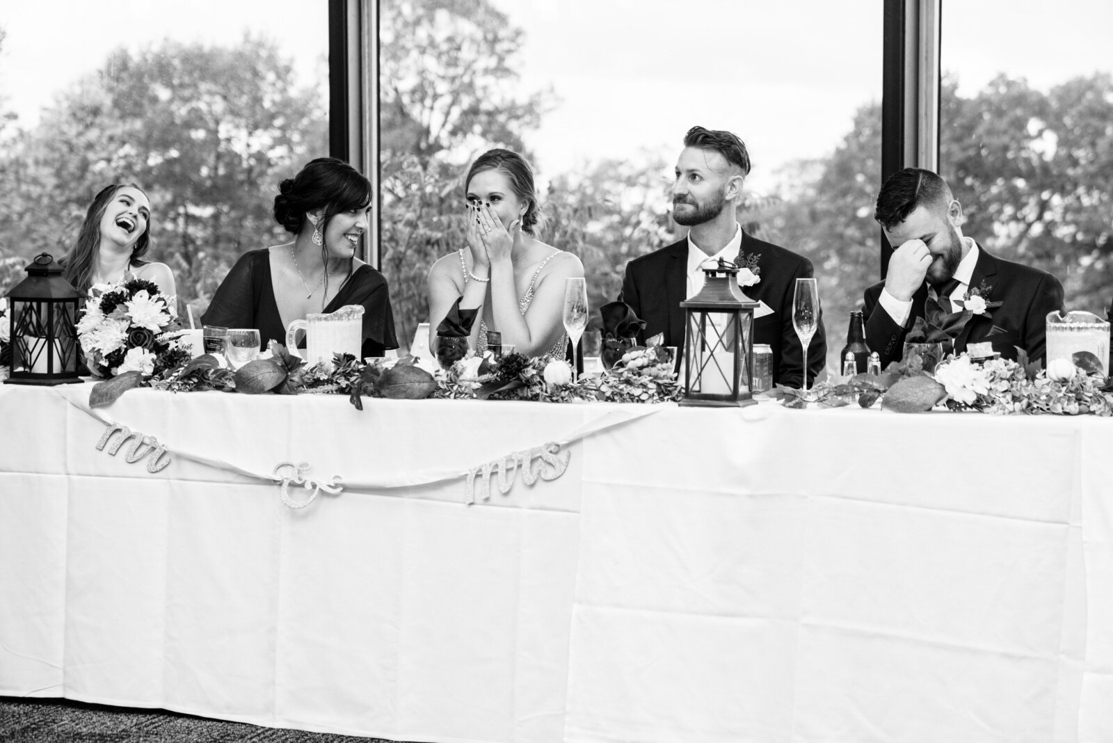 Bride and groom laugh at head table on wedding day.