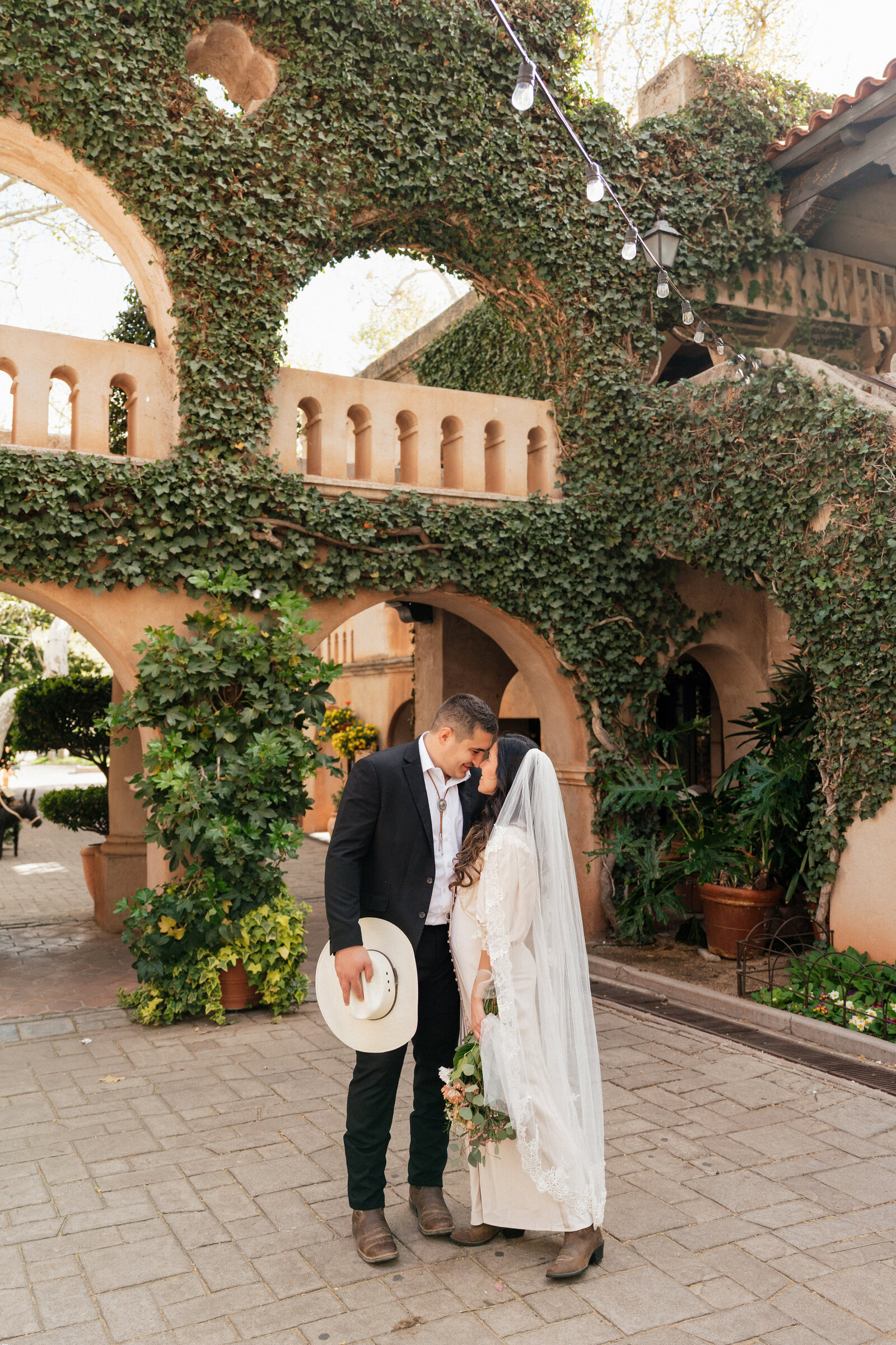 Bride and groom share an intimate moment under ivy-covered Spanish-style arches during their Tlaquepaque elopement in Sedona, Arizona.