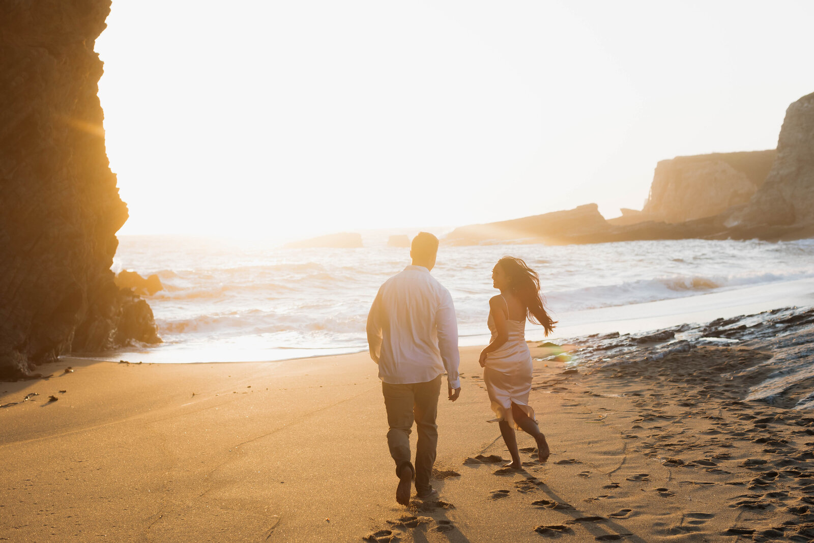 Couple walking along a sandy shore, captured in cinematic wedding photos that emphasize candid, emotional moments.