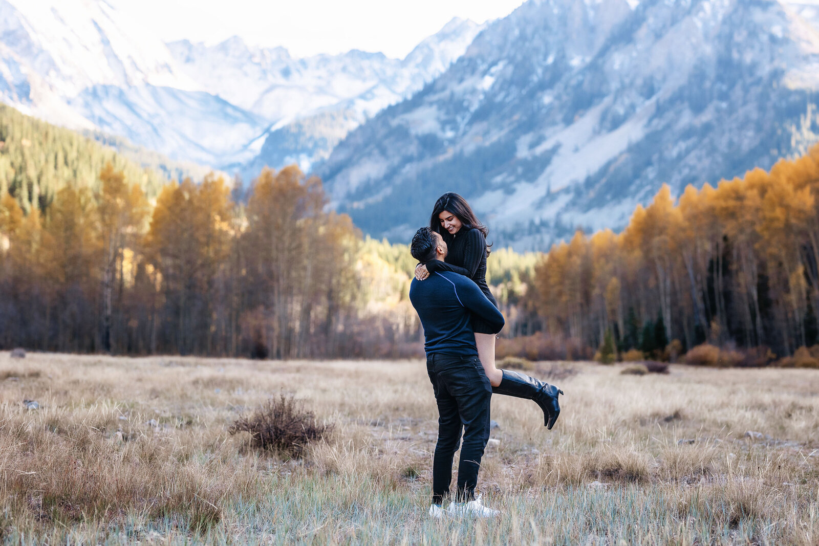 A man and woman hug after he just proposed to her in front of a majestic Aspen, Colorado mountain range.